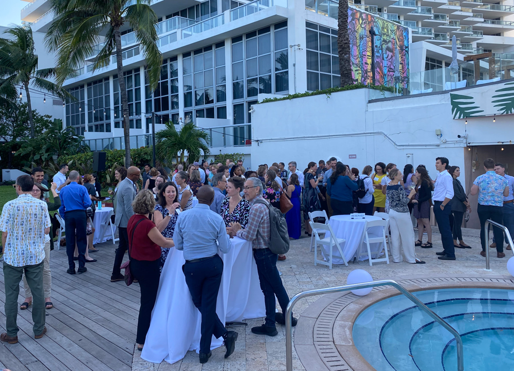 People networking by a pool outside of a hotel